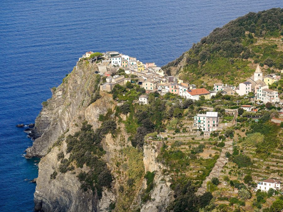 Corniglia auf einem erhöhten Felsvorsprung über der ligurischen Küste, mit Weinbergterrassen und der Kirche San Pietro